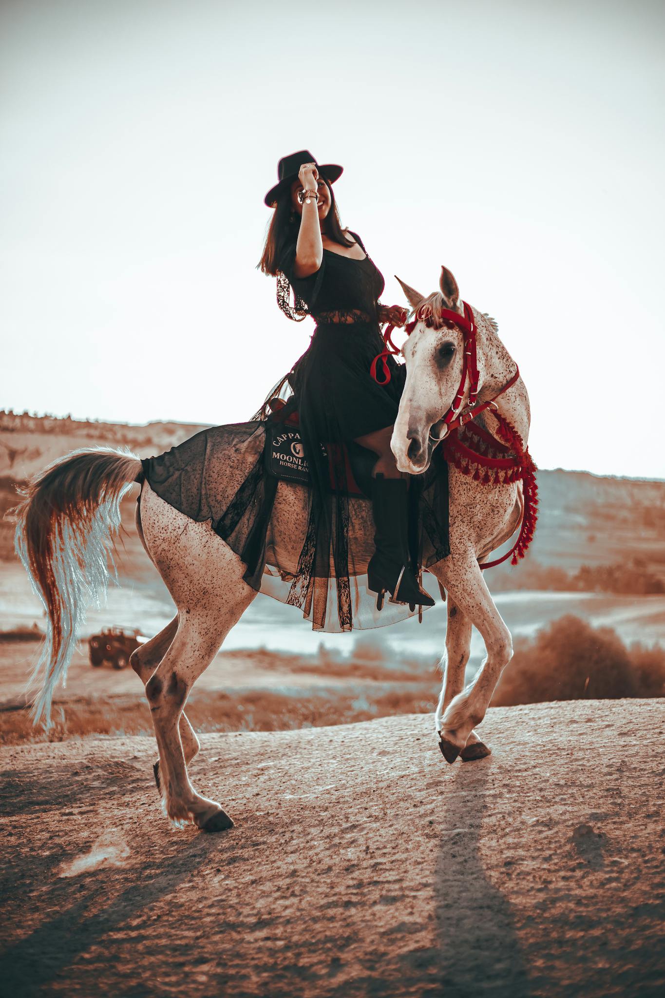 A majestic scene of a woman in black attire riding a horse in the desert, exuding elegance.
